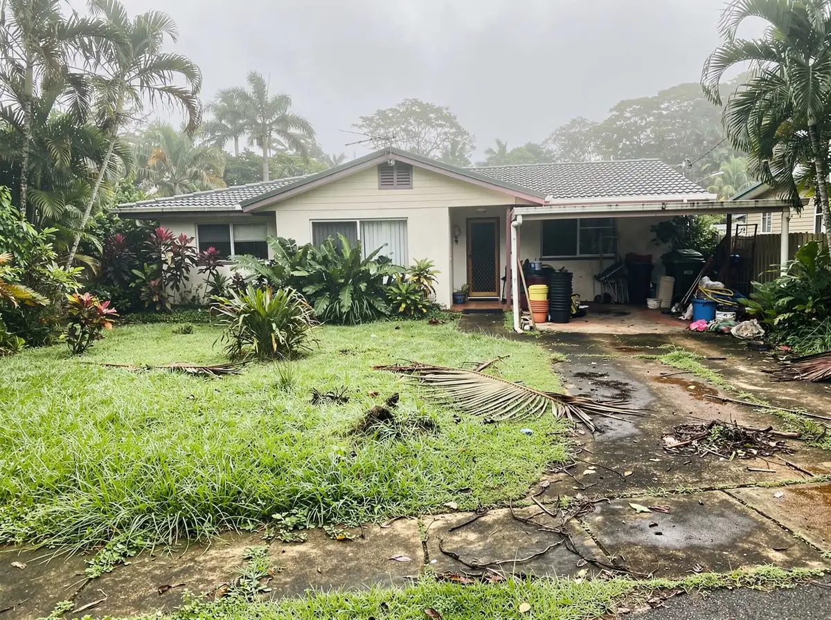 Before: overgrown wet-season lawn with fallen palm fronds and cluttered carport